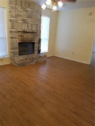 an empty room with wooden floor fireplace and chandelier