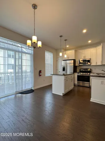 a view of a kitchen with stainless steel appliances granite countertop a stove top oven a refrigerator a sink and a wooden floor