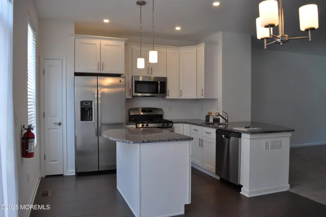 a kitchen with stainless steel appliances granite countertop a stove a refrigerator a sink and a microwave