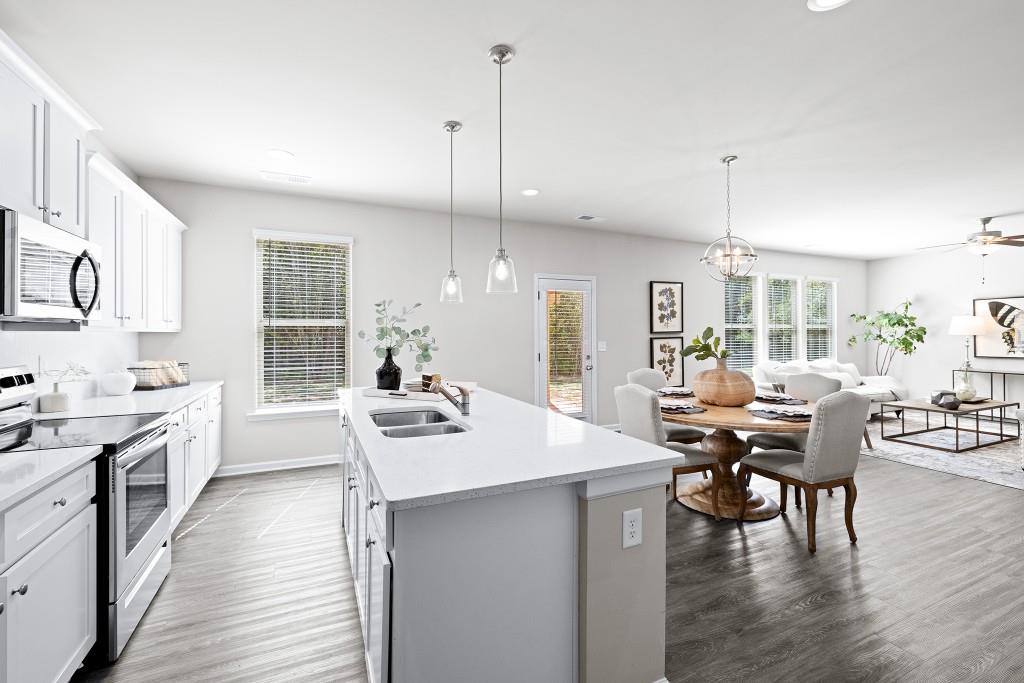 7 Purackal Lane Statham, GA 30666 - Photo 21 of 57 a view of a kitchen with kitchen island granite countertop a stove a sink a dining table and chairs with wooden floor
