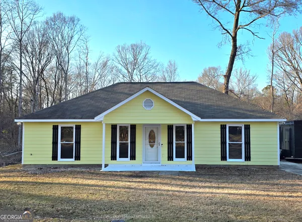 a front view of a house with a garden and tree