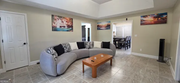 a living room with furniture a dining table and a refrigerator