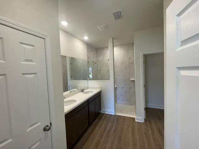 a bathroom with a granite countertop sink a toilet a glass door shower and a mirror