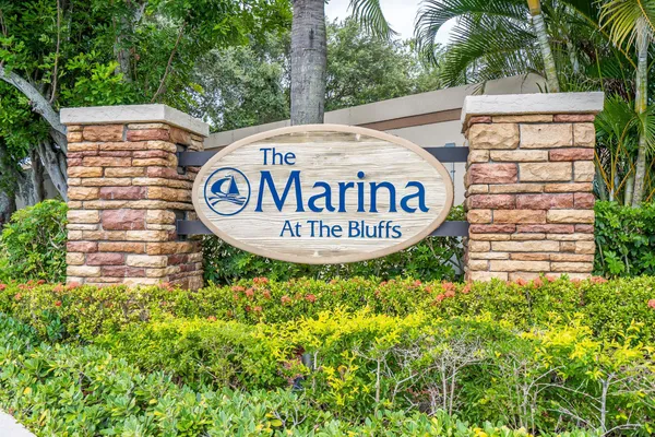 a sign board with a house and trees in the background