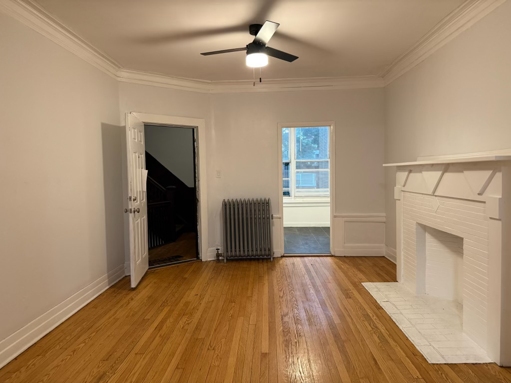 6928 South Green Street, Unit 1S Chicago, IL 60621 - Photo 2 of 12 an empty room with wooden floor fireplace and windows