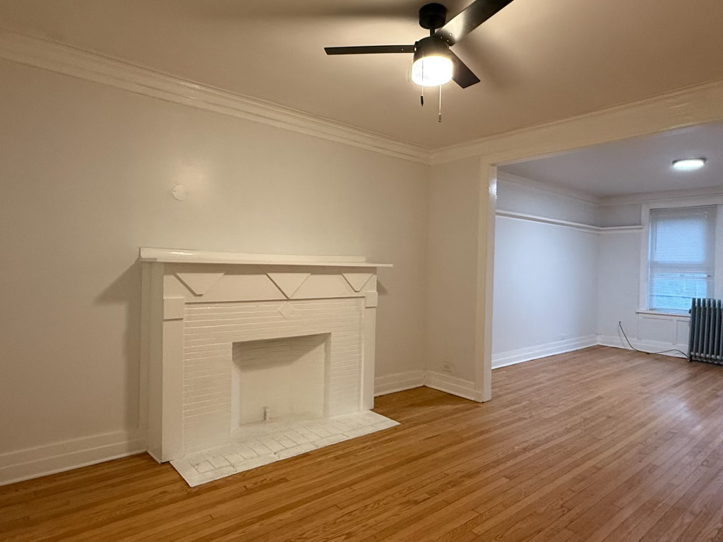 6928 South Green Street, Unit 1S Chicago, IL 60621 - Photo 4 of 12 a view of an empty room with wooden floor and a fireplace