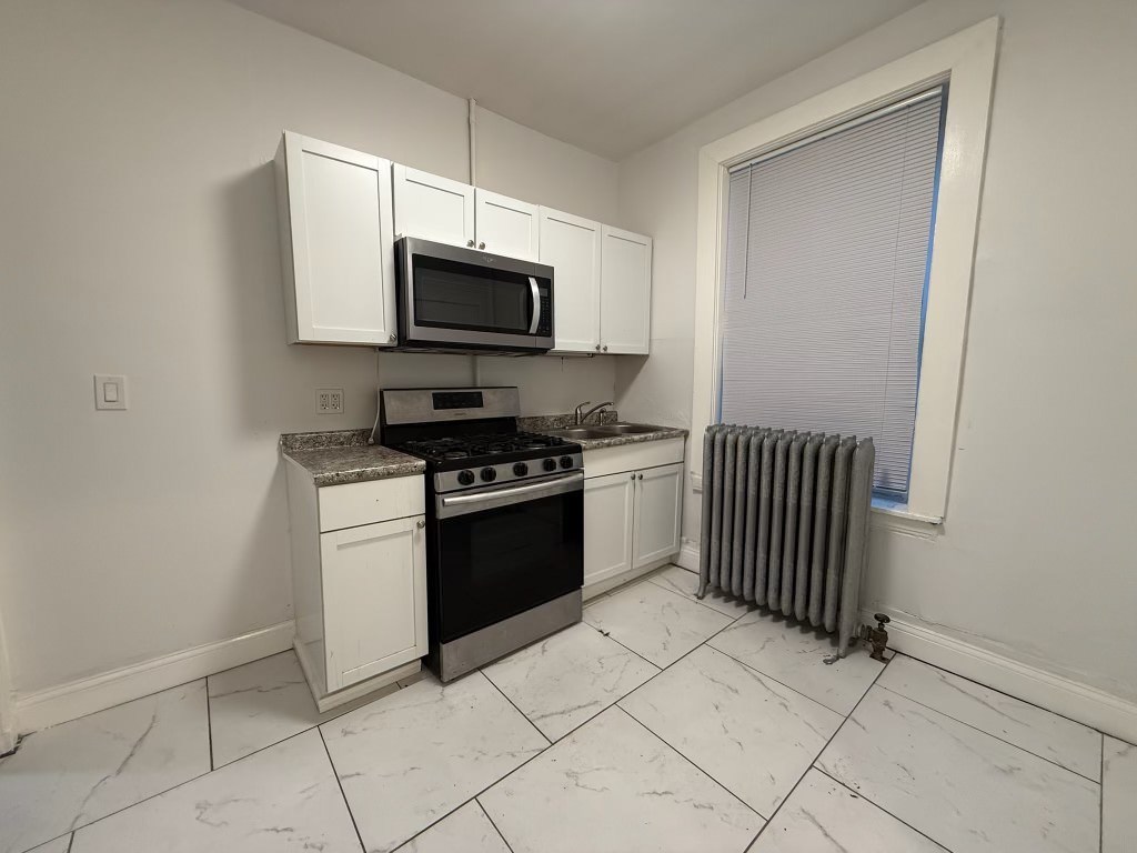 6928 South Green Street, Unit 1S Chicago, IL 60621 - Photo 5 of 12 a kitchen with stainless steel appliances a sink dishwasher stove and white cabinets