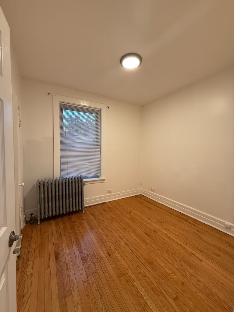 6928 South Green Street, Unit 1S Chicago, IL 60621 - Photo 10 of 12 an empty room with wooden floor and windows