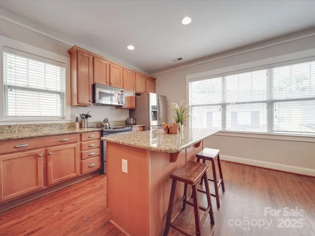 a kitchen with stainless steel appliances granite countertop wooden cabinets a stove a sink and a window