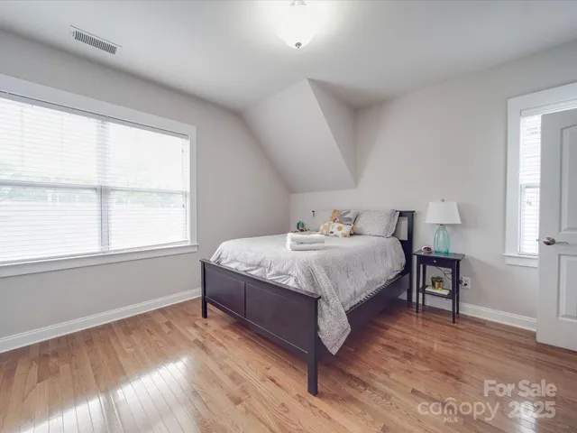 a spacious bedroom with a bed and wooden floor