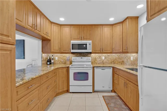 a kitchen with stainless steel appliances granite countertop a stove top oven a sink dishwasher and a refrigerator with wooden cabinets