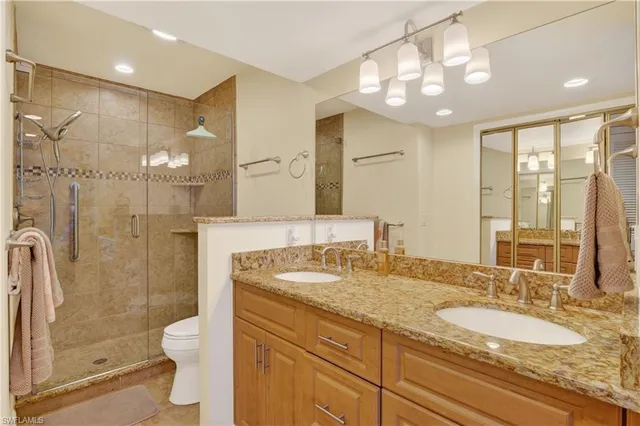 a bathroom with a granite countertop double vanity sink toilet and shower