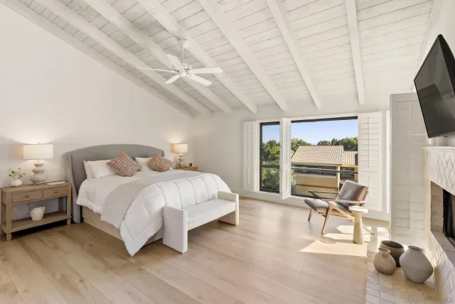 a bedroom with a bed a flat screen tv and chairs