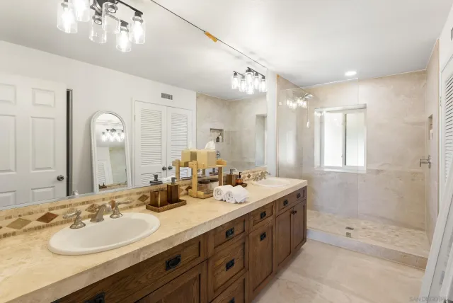 a bathroom with a double vanity sink mirror and shower