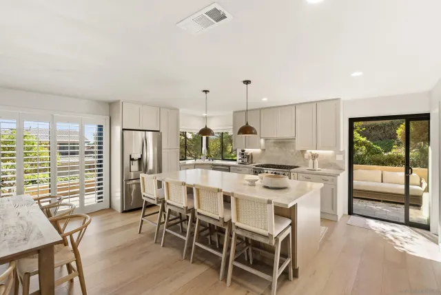 a kitchen with stainless steel appliances kitchen island granite countertop a stove a refrigerator a oven a sink with a dining table and chairs