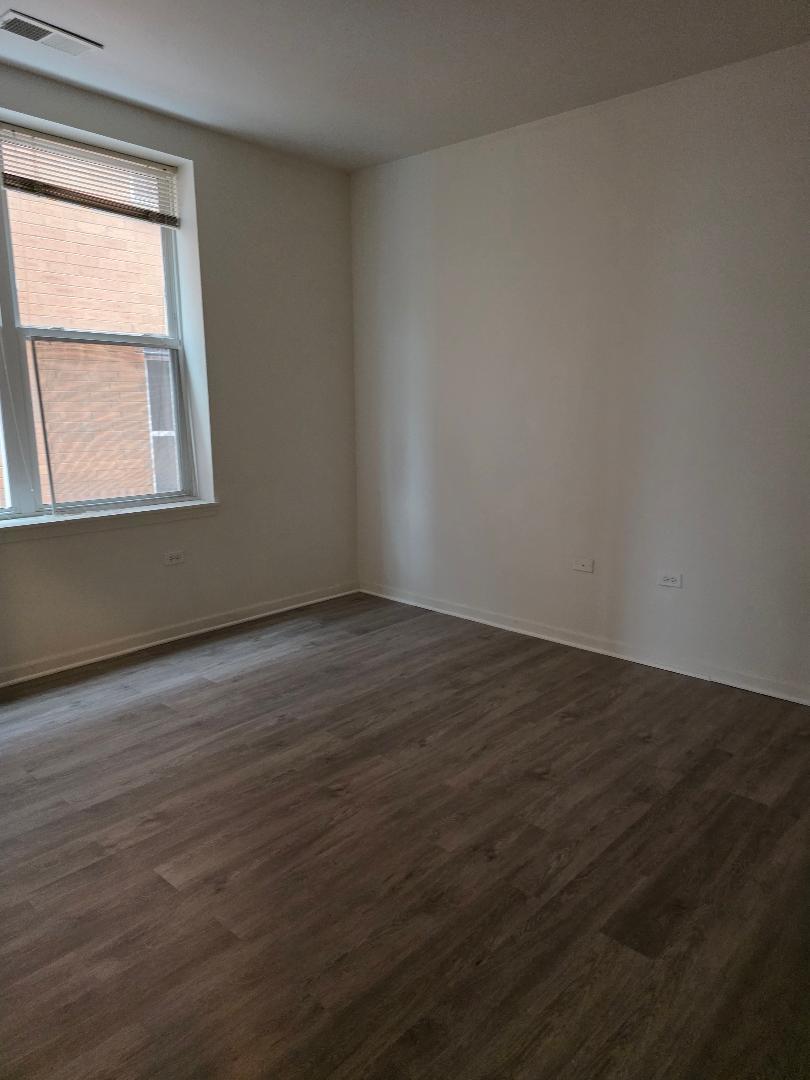 3506 South State Street, Unit 208 Chicago, IL 60609 - Photo 8 of 14 a view of an empty room with wooden floor and a window