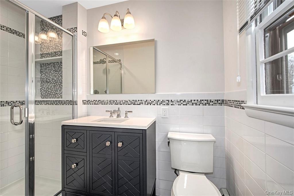 74 Edgewood Road Ossining, NY 10562 - Photo 13 of 29 Bathroom featuring a glass-enclosed shower, dark wood vanity and tile accents