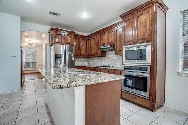 a kitchen with stainless steel appliances granite countertop a stove a sink and a microwave