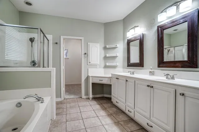 a spacious bathroom with a double vanity sink mirror and bathtub