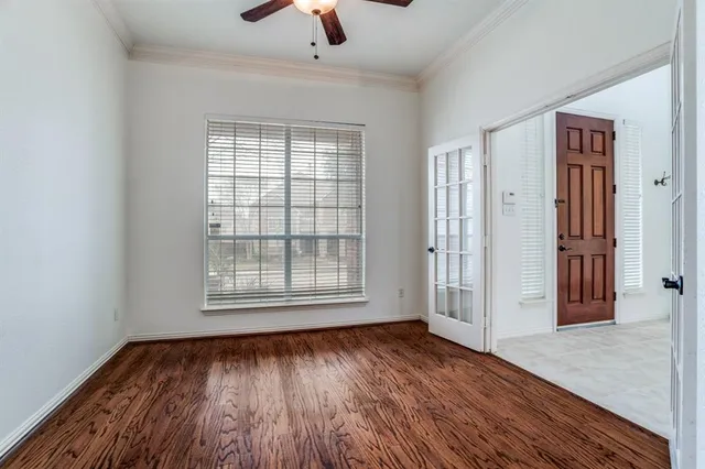 an empty room with wooden floor chandelier and windows