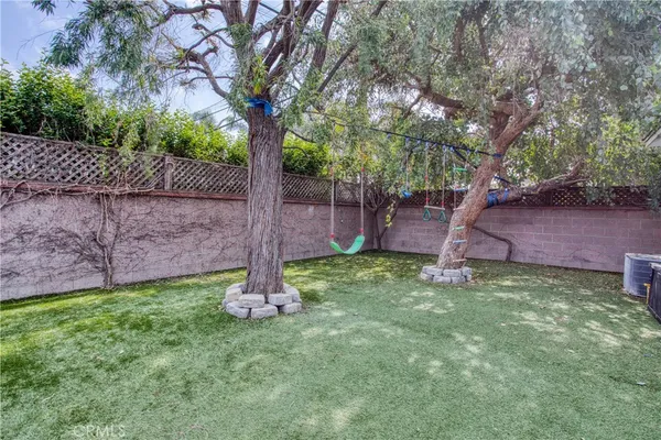 a backyard of a house with plants and large tree