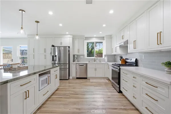 a large kitchen with stainless steel appliances sink a microwave and cabinets