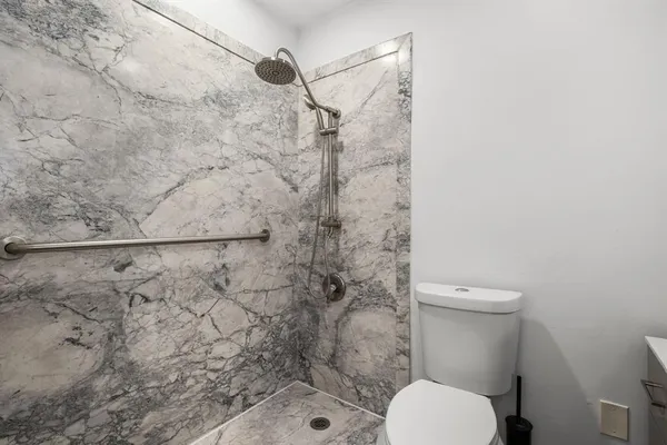 a white toilet sitting next to a shower