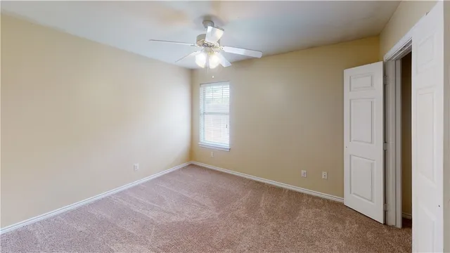 an empty room with a chandelier fan and windows