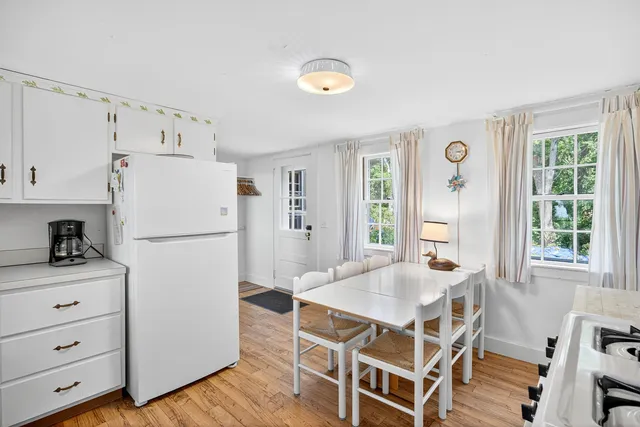 a kitchen with a table chairs refrigerator and windows