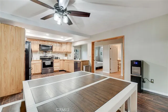 a room with stainless steel appliances granite countertop a refrigerator a stove and a sink with cabinets