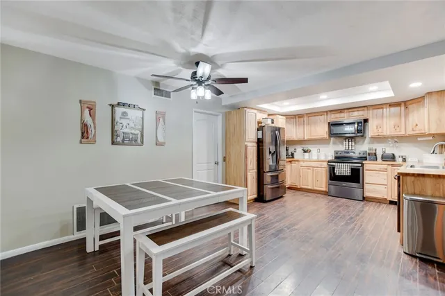 a open kitchen with stainless steel appliances a stove a refrigerator cabinets and wooden floor