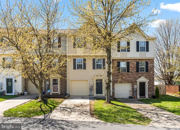 a front view of a house with a yard and large tree