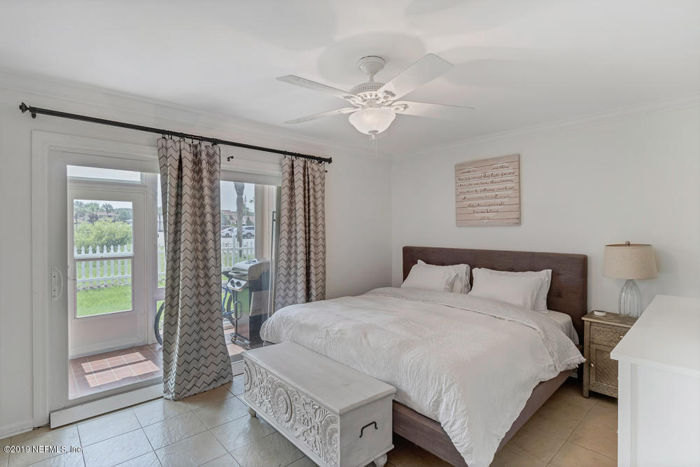 4 Ocean Trace Road, Unit 6 St. Augustine, FL 32080 - Photo 12 of 31 a bedroom with a large bed and a chandelier