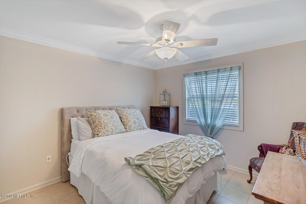 4 Ocean Trace Road, Unit 6 St. Augustine, FL 32080 - Photo 16 of 31 a bedroom with a large bed and a chandelier