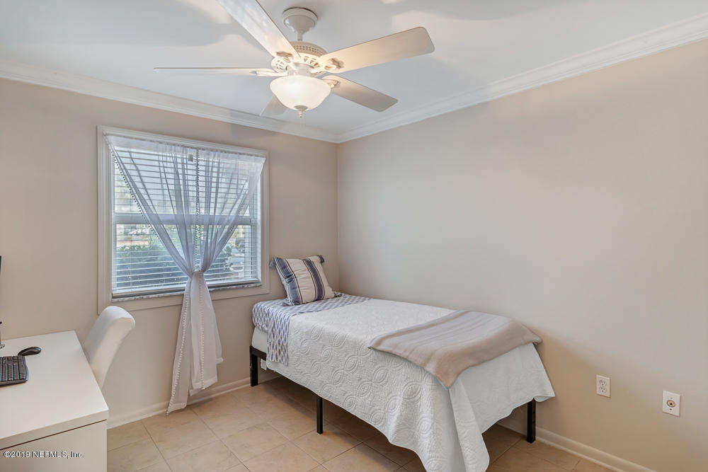 4 Ocean Trace Road, Unit 6 St. Augustine, FL 32080 - Photo 19 of 31 a bedroom with a bed and a chandelier