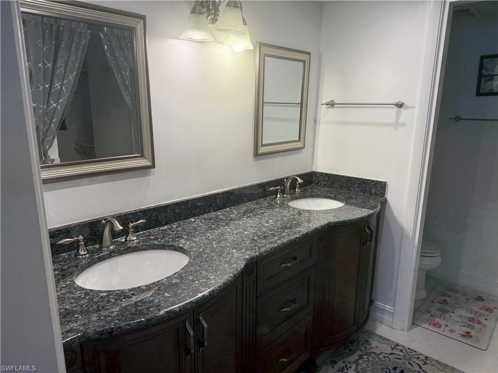 5535 Rattlesnake Hammock Road, Unit 104 Naples, FL 34113 - Photo 20 of 30 a bathroom with a granite countertop sink and a mirror