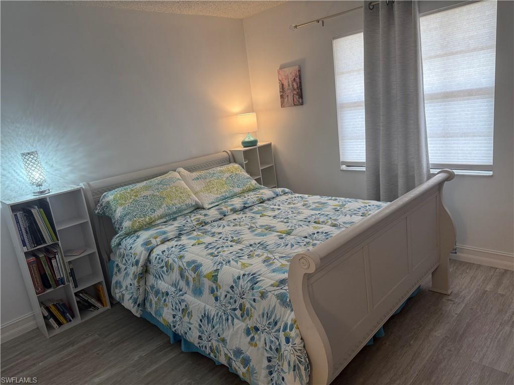 5535 Rattlesnake Hammock Road, Unit 104 Naples, FL 34113 - Photo 25 of 30 a bedroom with a bed and wooden floor