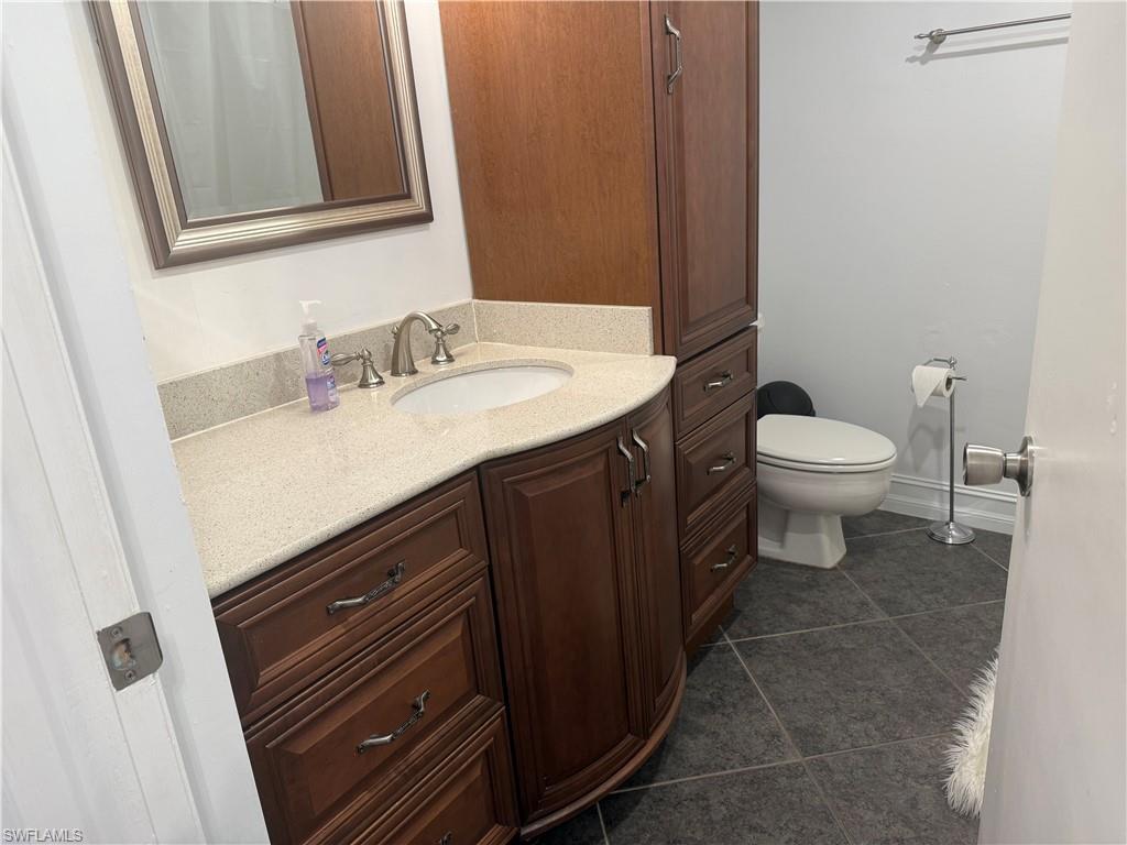 5535 Rattlesnake Hammock Road, Unit 104 Naples, FL 34113 - Photo 27 of 30 a bathroom with a granite countertop sink toilet and mirror