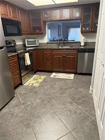 a kitchen with stainless steel appliances granite countertop a stove a sink and a microwave