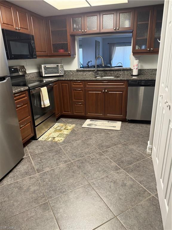 5535 Rattlesnake Hammock Road, Unit 104 Naples, FL 34113 - Photo 5 of 30 a kitchen with stainless steel appliances granite countertop a stove a sink and a microwave