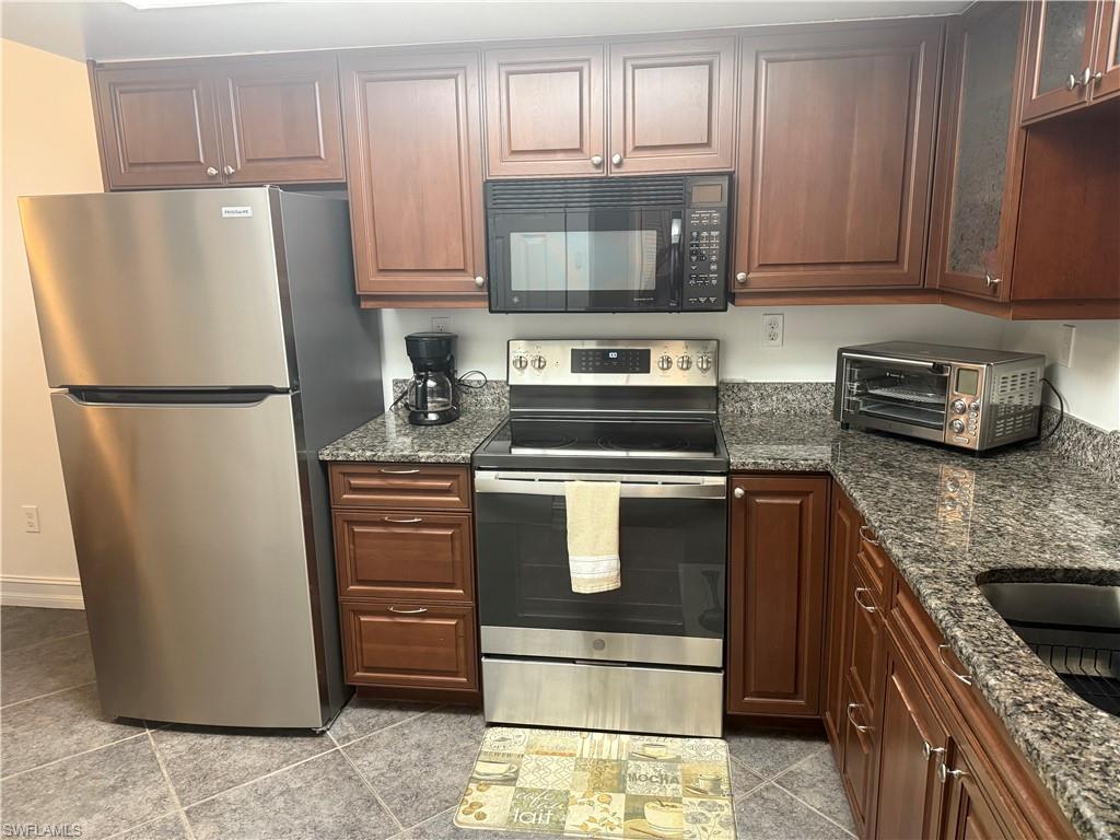 5535 Rattlesnake Hammock Road, Unit 104 Naples, FL 34113 - Photo 7 of 30 a kitchen with refrigerator a microwave a stove and cabinets
