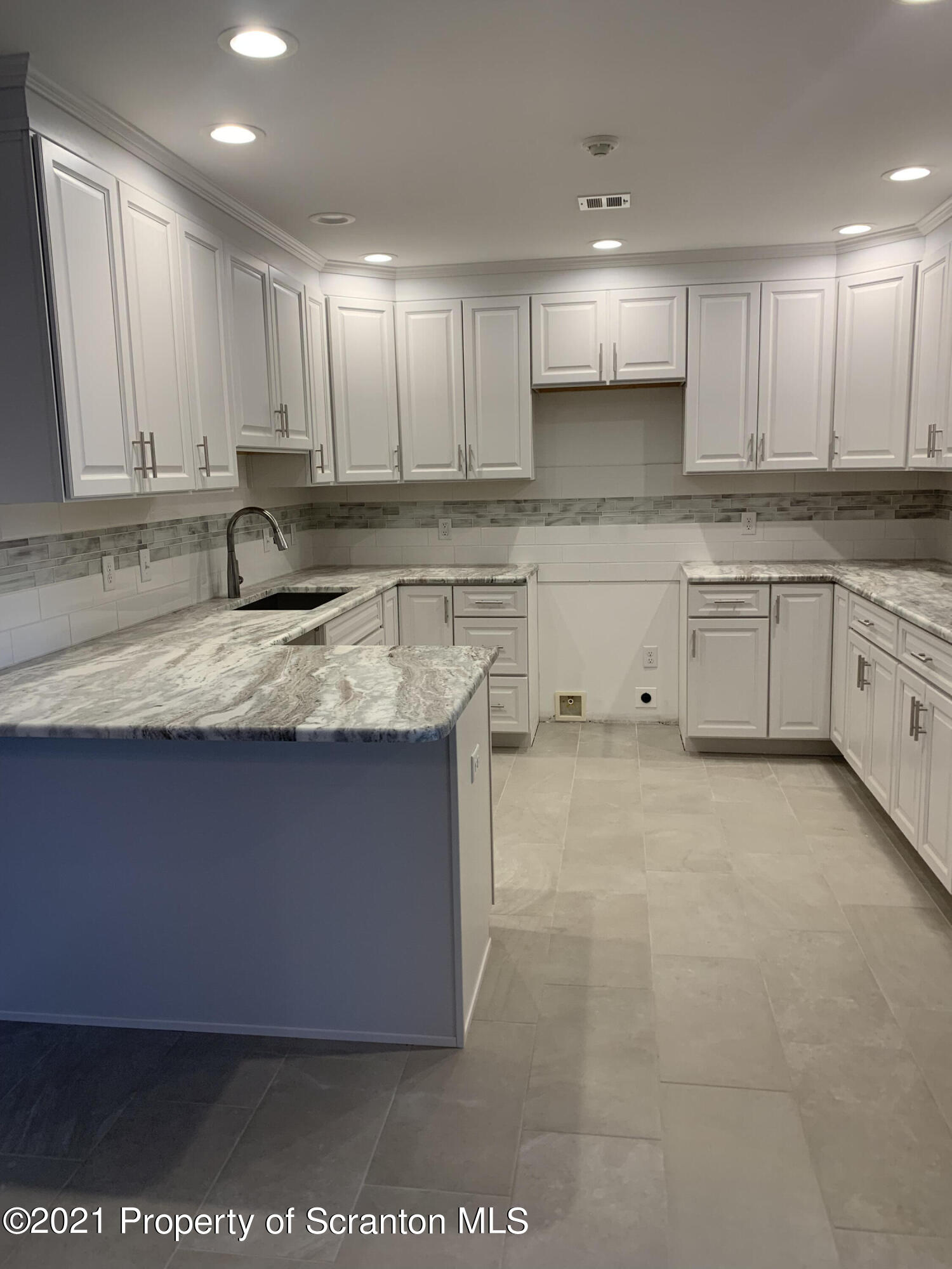 104 Deerfield Drive Eynon, PA 18403 - Photo 4 of 25 a kitchen with granite countertop a sink white cabinets and stainless steel appliances