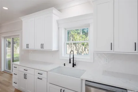 a kitchen with white cabinets and a window