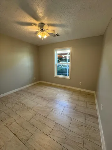 an empty room with a chandelier fan and windows