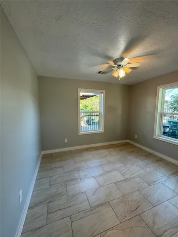 an empty room with windows and fan