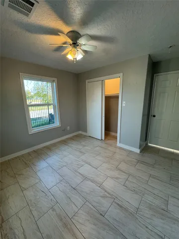 an empty room with windows and chandelier fan