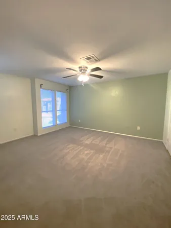 an empty room with a chandelier fan and windows