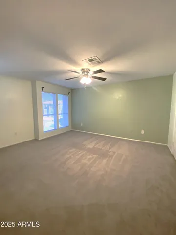 an empty room with a chandelier fan and windows