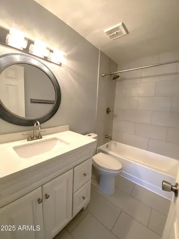 a bathroom with a granite countertop toilet sink and mirror