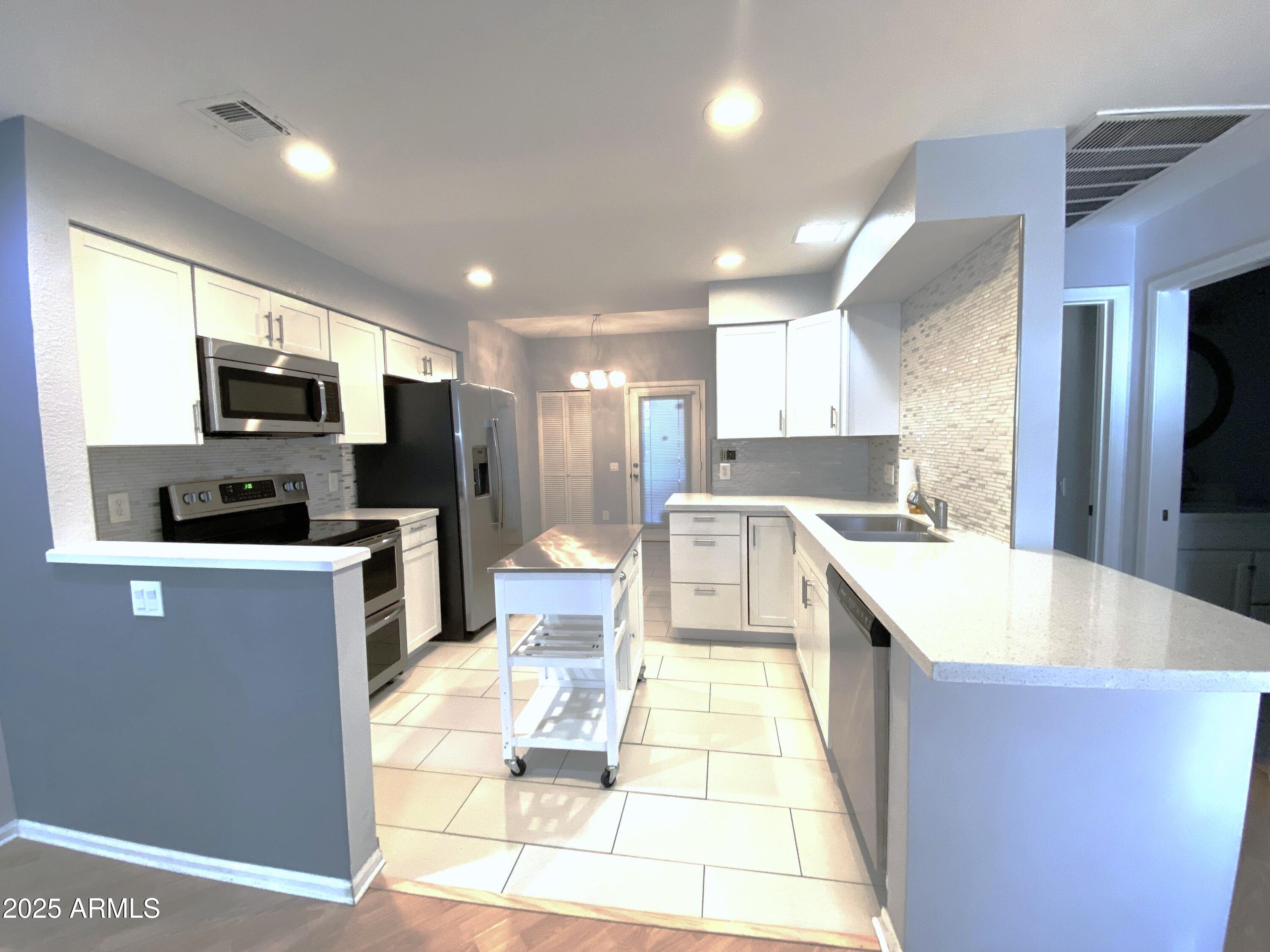 101 North 7th Street, Unit 270 Phoenix, AZ 85034 - Photo 6 of 23 a large kitchen with stainless steel appliances kitchen island granite countertop a sink a stove a microwave a counter top and cabinets